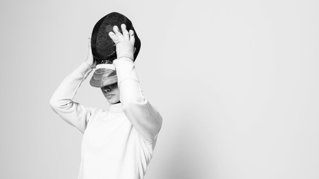 A left-handed fencer putting on her mask.