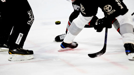 A close-up action shot of hockey players mid-stride, handling the puck, showcasing precision and skill left-handed shooters are known for on the ice.