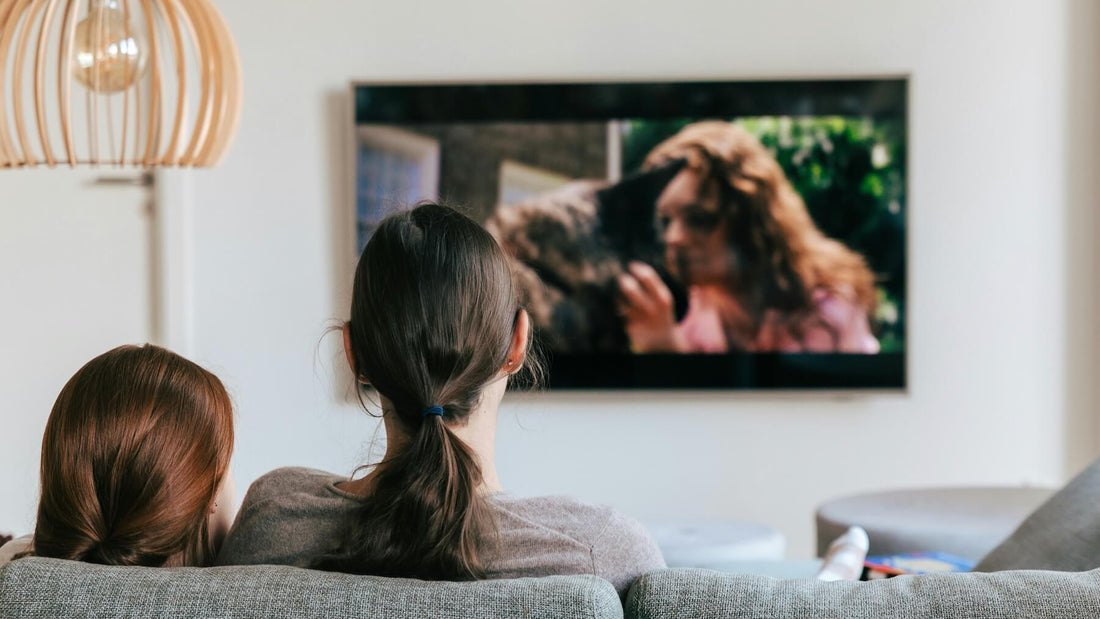 Two people sitting in a cozy living room watching TV, representing the impact of left-handed TV writers behind the scenes.