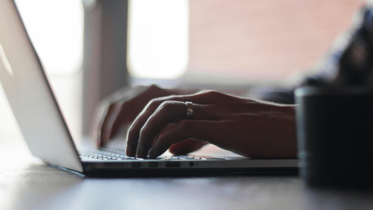 Close-up of a person typing on a laptop, highlighting the everyday creativity of left handed writers.