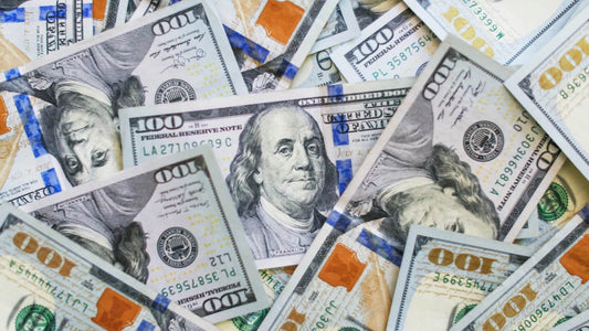 Close-up of $100 bills representing the fortunes of the richest left-handed people.