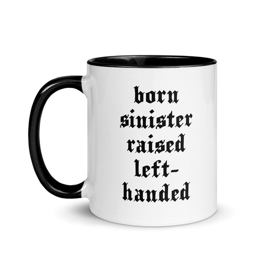White ceramic mug for left-handers featuring black gothic text "Born Sinister Raised Left-Handed" with black handle and interior.