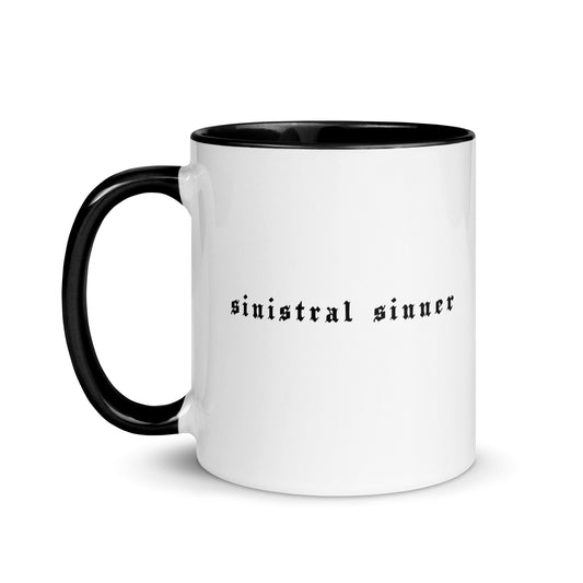 White ceramic mug for left-handers featuring black gothic text "Sinistral Sinner" with black handle and interior.
