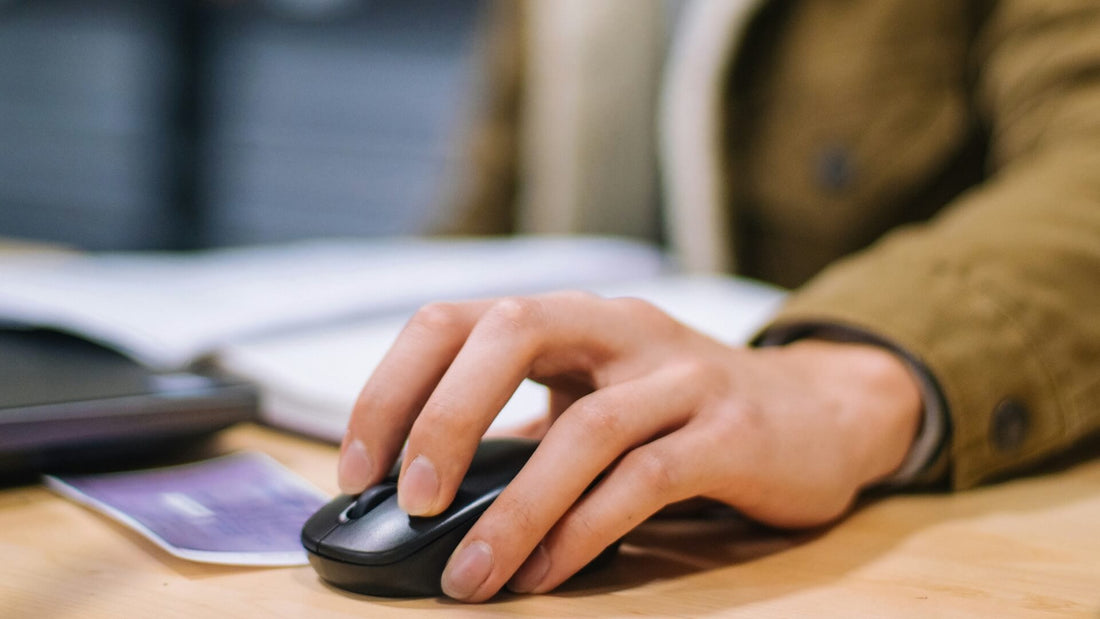 Person using a black cordless computer mouse with their left hand.