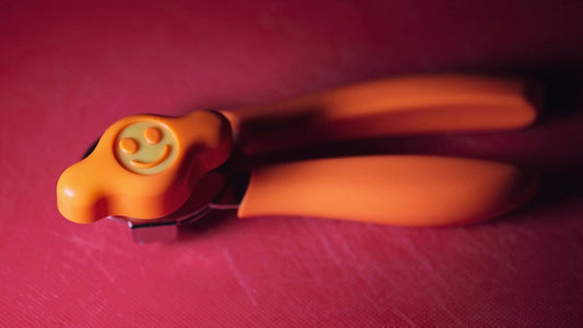 Orange smiley left-handed can opener on a red plastic cutting board.