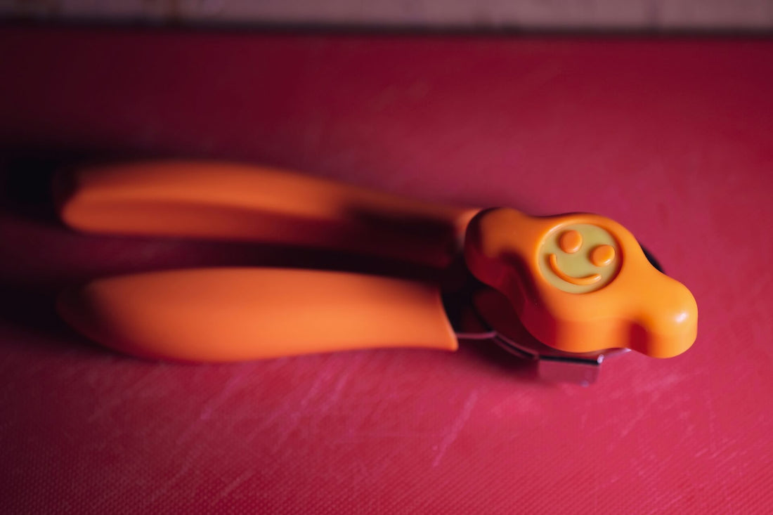 Orange smiley left-handed can opener on a red plastic cutting board.