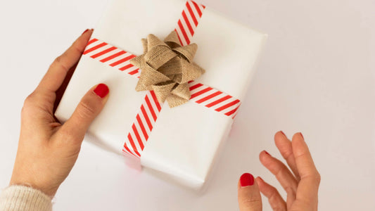 Left hand holding a neatly wrapped gift with a ribbon, symbolizing holiday giving for left-handed people.