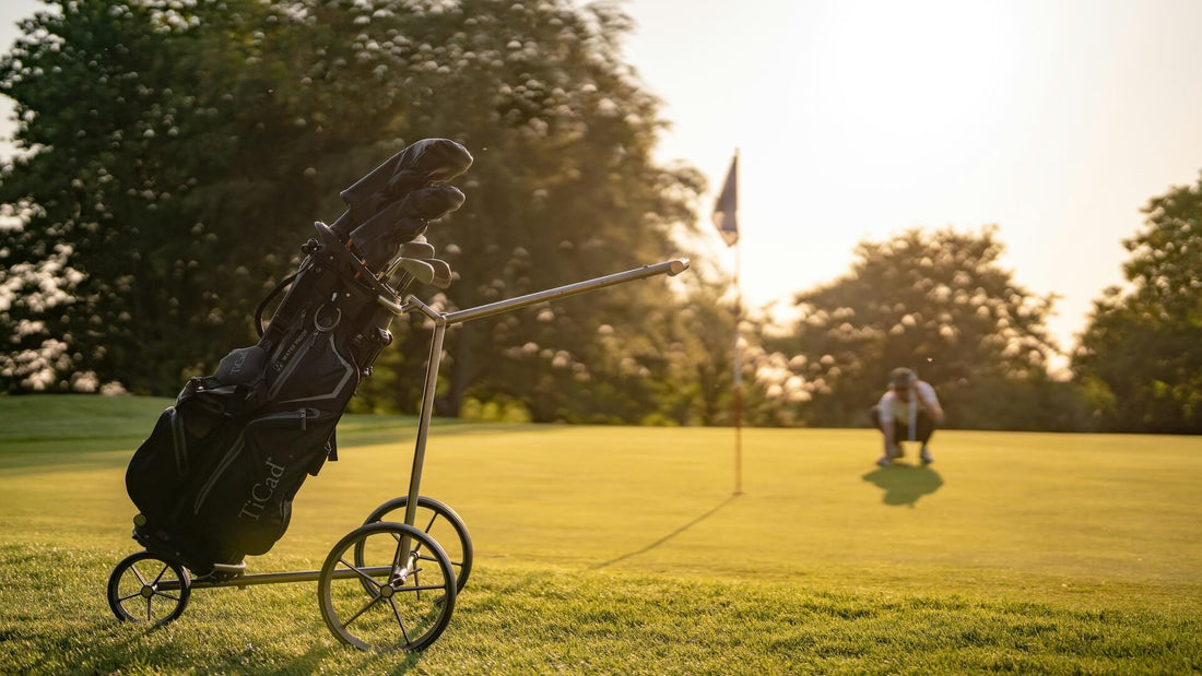 Golf bag standing on the green in the foreground with a golfer judging a putt during golden hour.