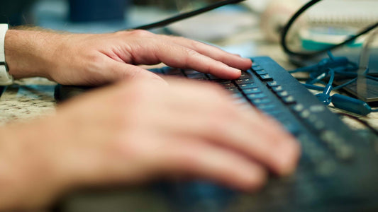 Person typing on black computer keyboard.