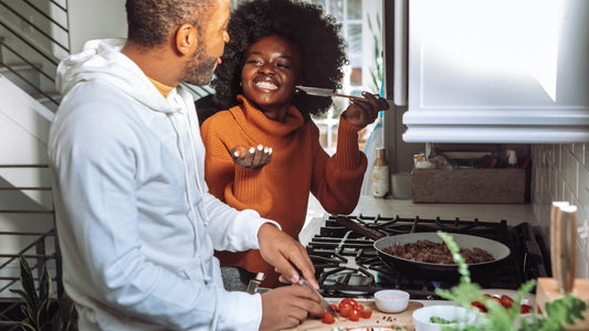 Happy left-handed couple preparing a meal together, laughing and enjoying time in the kitchen.