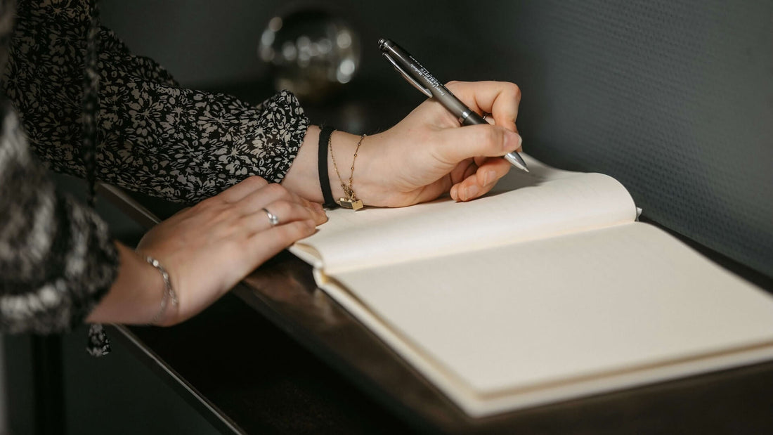 Close-up of a left-handed woman writing in a guestbook.