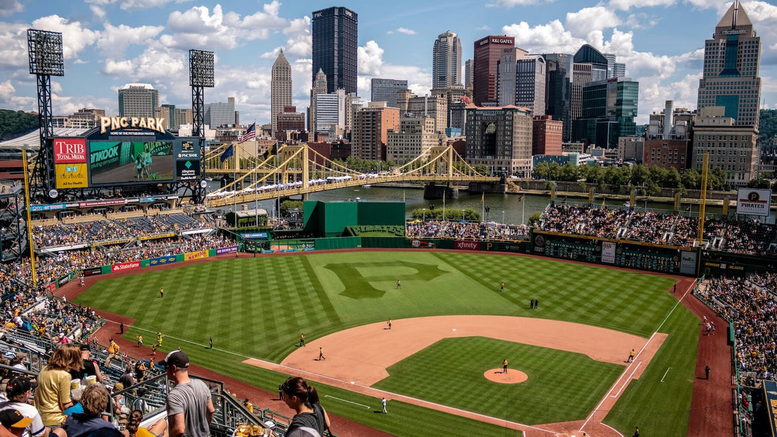 Baseball game in progress at PNC Park, with players on the field and fans in the stands under a bright sky.