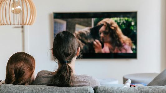 Two people sitting in a cozy living room watching TV, representing the impact of left-handed TV writers behind the scenes.