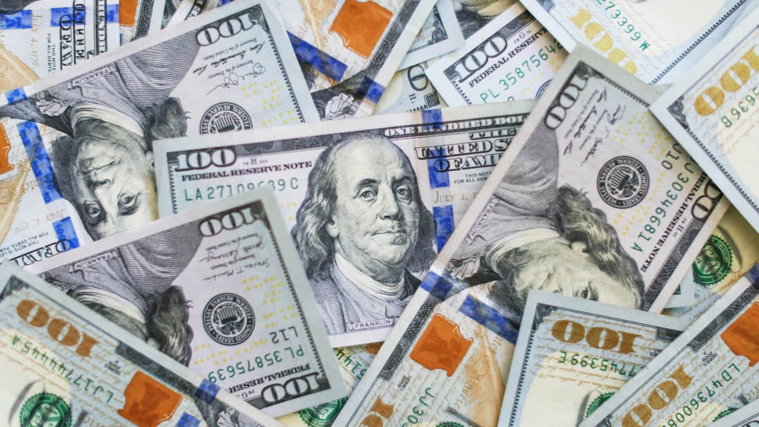 Close-up of $100 bills representing the fortunes of the richest left-handed people.