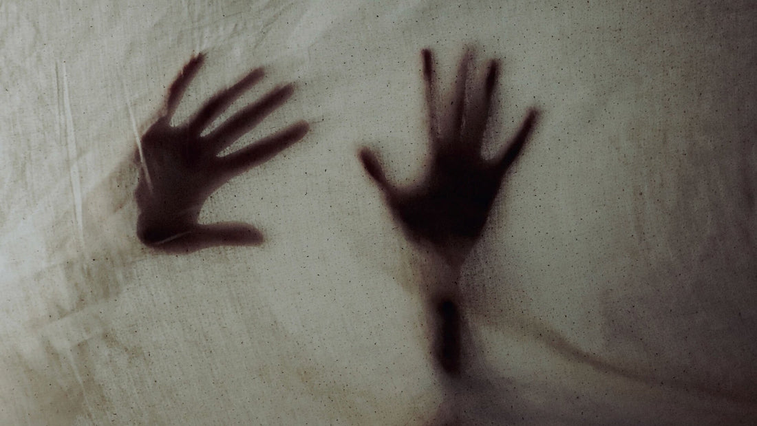Two hands pressed behind a sheet, creating an eerie silhouette.