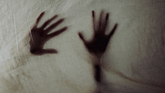 Two hands pressed behind a sheet, creating an eerie silhouette.