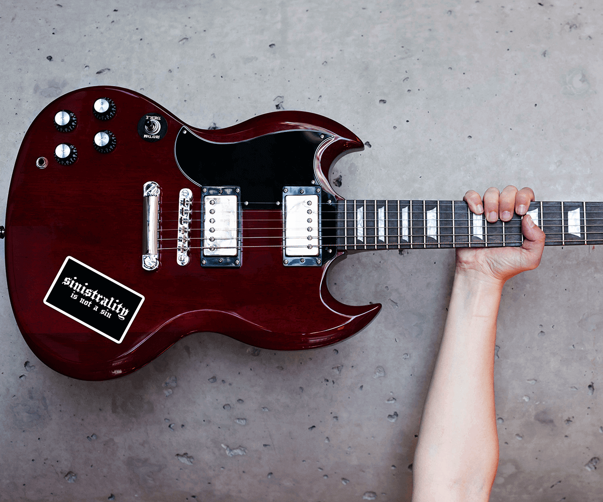 Left-handed guitar Gibson SG with a sticker featuring the black gothic text "Sinistrality is not a sin."